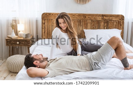 Sweet conversations of lovers concept. Man and woman talking in bed in bedroom interior
