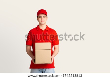 Parcel shipping and home delivery. Courier holds boxes, free space, studio shot