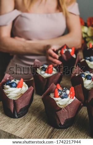 Woman hold cupcake in her hand. White and orange roses on background. birthday or wedding party concept.