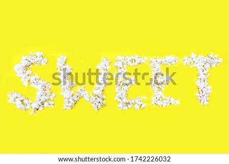 The inscription Sweet is written in white flowers of lilac on a yellow background. The word Sweet is written with lilac flowers. Flower inscription Sweet. Background for a greeting card. Wedding