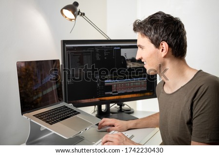 this content creator is a professional video editor who cuts and edits an online video on his desk with his computer Royalty-Free Stock Photo #1742230430