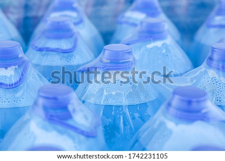 close-up of large blue bottles of drinking water Packed in polyethylene, transparent film in a warehouse in the store.Plastic transparent bottle with blue lid