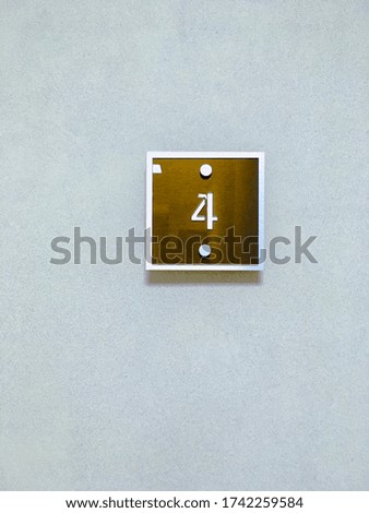 Brown plate on the wall with the number 4. Concept: apartment number, floor number