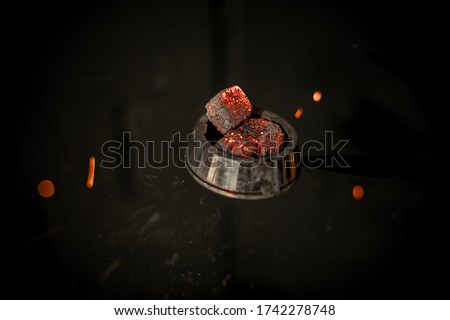 Hookah hot coals for smoking hookah and relaxation. Dark background, smoke, sparks.