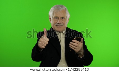 Elderly stylish grandfather caucasian mature man using app on smartphone for successful online shopping. Thumbs up. Chroma key. Old senior grandparent in fashion clothes browsing on mobile phone