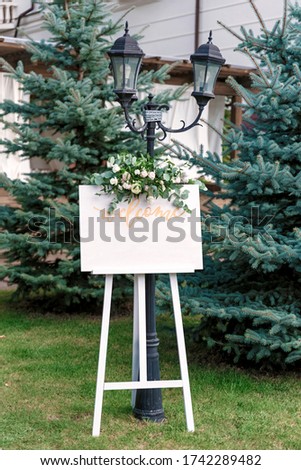 Wedding white Board Mockup easel with welcome sign decorated with flowers, outdoors. Greeting card template