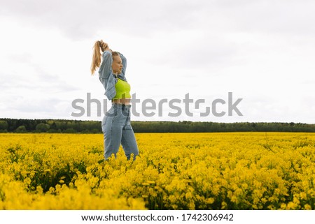 a blonde girl walks in a rapeseed field in the summer