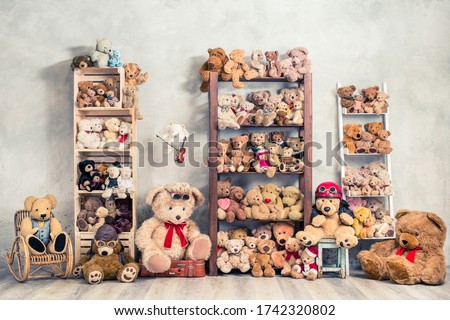 Retro Teddy Bear plush toys great collection on wooden shelving, antique rocking chair, old stool, boxes front loft concrete wall background. Childhood nostalgia concept. Vintage style filtered photo Royalty-Free Stock Photo #1742320802