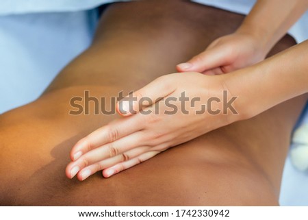 brazilian woman getting back and shoulders massaging in outdoor spa Ayurveda centre in India green tropical background