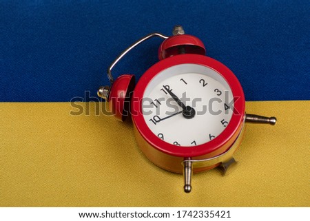Ukrainian flag and vintage alarm clock close up. Time to learn Ukrainian. Time to travel around Ukraine.