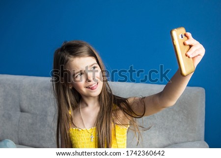 girl takes a selfie on her phone in a room with blue walls