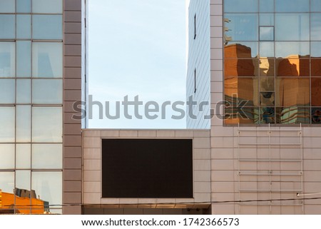 TV screen on business building. Large blank black screen of TV layout Billboard. Template for placing ads on wall of modern building. Empty large Billboard black led screen on building