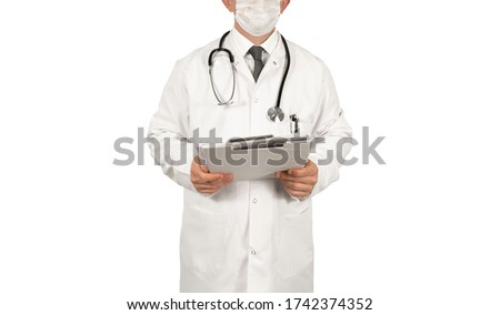 Male doctor standing in front of white background, wearing a mask and a white coat holding a file folder in his hand with a stethoscope around his neck.