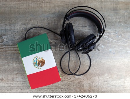 Headphones and book. The book has a cover in the form of Mexico flag. Concept audiobooks. Learning languages.