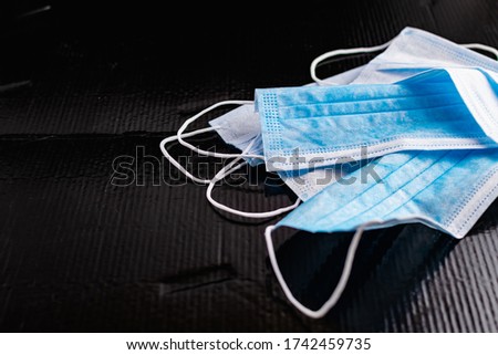 Disposable medical masks to protect against infections and viruses. White and blue layers with elastic bands for ears, on a black background