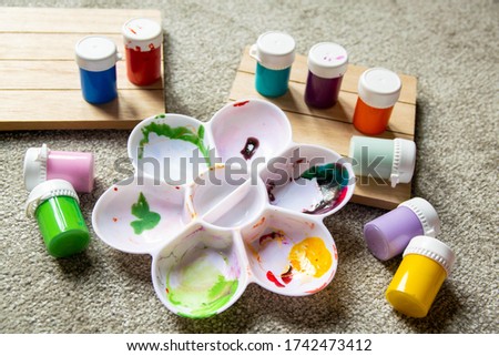 Various children's paint pots with mixing tray. Family fun activity to keep kids busy whilst staying at home. Indoor recreation. Creative, art supply, drawing, imagination, learning concept background