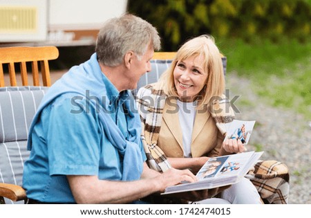 Senior couple looking through their family photo album near RV on camping site