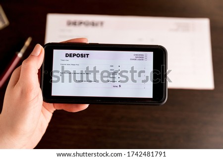 Man Taking Photo Of Cheque To Make Remote Deposit In bank.