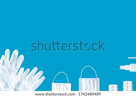 medical masks, gloves, antiseptic, syringe and tablets on a blue background, place for text, top view