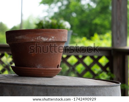 Rustic, clay pot sitting on a washtub on the front porch.