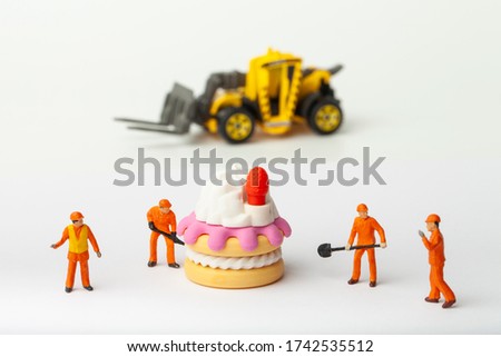 Miniature people move cake with strawberry, cooking and decoration concept. The concept of a collective solution to any problem.