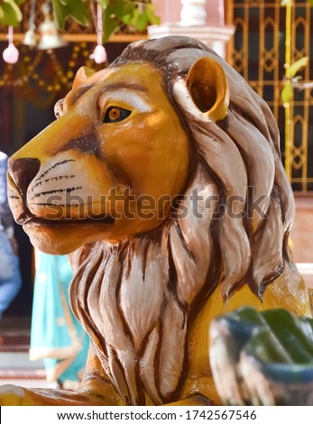 This is a realistic image of a lion statue with a blurred background, showing the craftsmanship and detail of the sculpture. The lion statue expressing power and majesty.