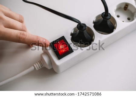 A woman turns on an electric surge protector. Protection of household appliances from electrical interference. Home safety Royalty-Free Stock Photo #1742571086