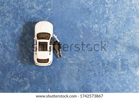 White car and car keys on a blue background. Holiday gift for daddy's day. Copy space.