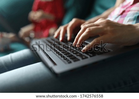 Close-up of person working on laptop sitting on sofa. Young female typing on grey modern gadget. Freelancer on quarantine period. Technology and remote job from home concept