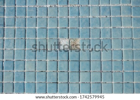 Two holes together on the empty pool floor. Stoneware swimming pool floor in which two blue tiles are missing.