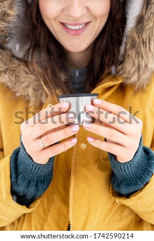 Woman Drinking A Hot Drink While Snow Is Falling Around Her