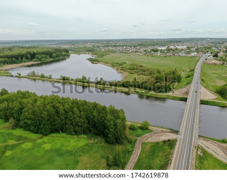 Beautiful panoramic landscape from the height of the bridge over the river. Traffic of cars on the bridge over the river on which the cargo ship sails. the picture from the drone