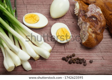Boiled eggs, fresh chives and smoked chicken laid out on a board