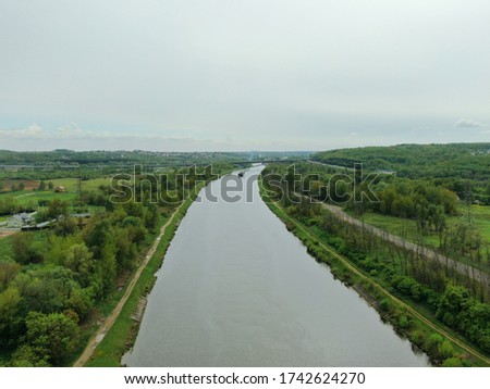 Beautiful panoramic landscape from the height of the bridge over the river. Traffic of cars on the bridge over the river on which the cargo ship sails. the picture from the drone
