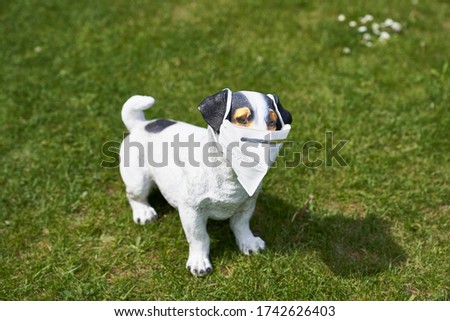 kitschy dog figure on lawn with kn95 protective mask