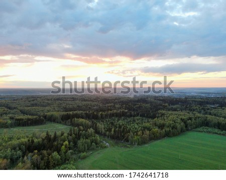 Beautiful panoramic landscape from the height of the green field against the background of the forest. Picture of beautiful nature from the drone