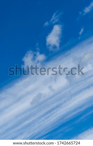 Blue sky with beautiful striped fluffy white clouds. The mood of happiness, love and delight. Great background for any design. Place for text and any items.