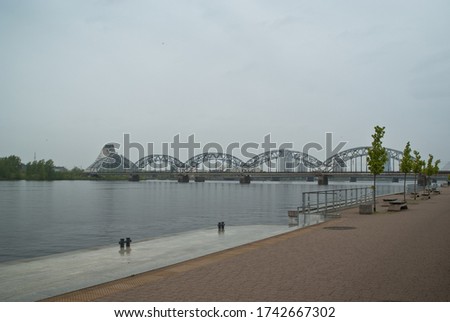 Riga embankment, photo taken on a cloudy day, with the railway bridge and the national library in the background.