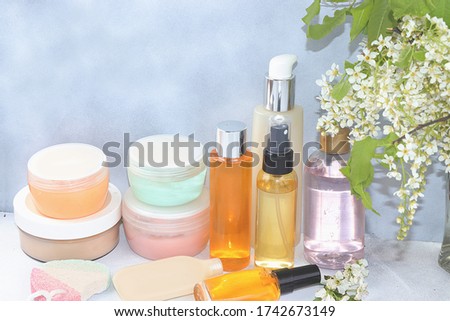 Spa ingredients, a set of cosmetic oils and creams for skin and body care on a gray background with branches of blooming cherry. Shopping concept and modern woman, sale, selective focus