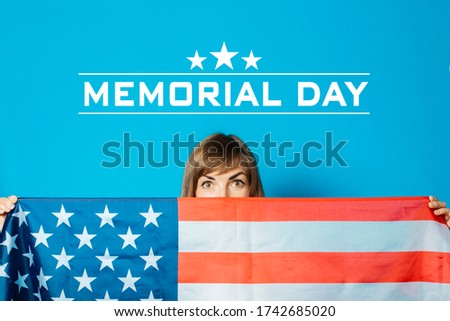 Young woman holds the USA flag in front of her on a blue background. USA Visa Concept, English, Independence Day, July 4th, Memorial Day. Travel to the USA.