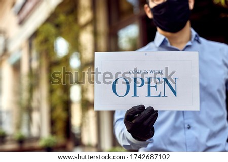 Close-up of cafe owner reopening and holding open sign.