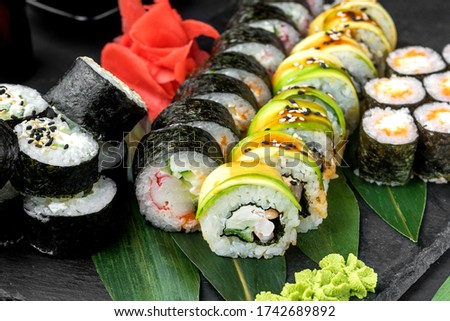 Sushi rolls set served on black stone slate on dark background