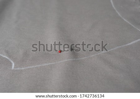 A pin is seen on a coffee color knit fabric