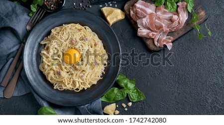 spaghetti Carbonara with yolk and bacon on a dark background