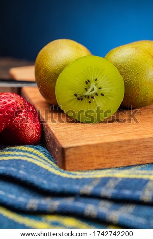 kiwi and strawberry on a wood table with blue and black background