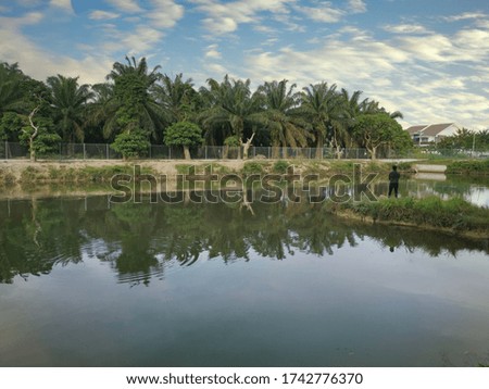 unrecognizable man standing fishing at the pond