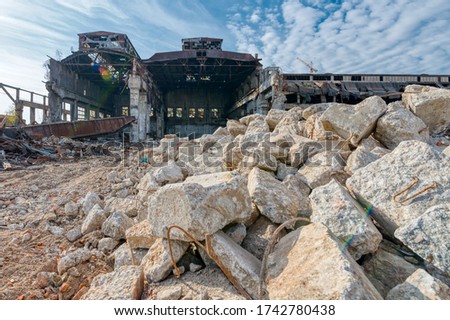 Dilapidated building of an old factory. In the foreground are large shattered pieces of concrete.