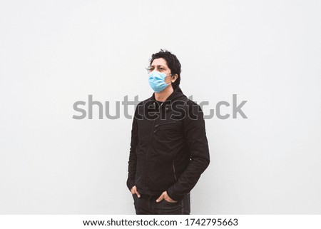 Man in black wearing a protective medical face mask in the city environment during coronavirus pandemic. Isolated on a white background.