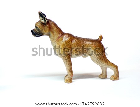 A statuette of a boxer dog isolated on a white background. Dog in profile from the side. Figure and children's toy in the form of a dog.