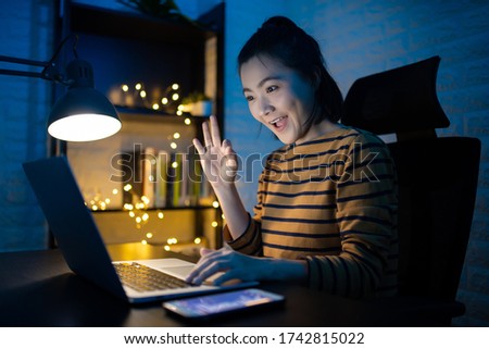 Asian woman happy smiling working on a laptop at the night at home and showing OK sign. WFH. Work from home avoid COVID 19 concept.